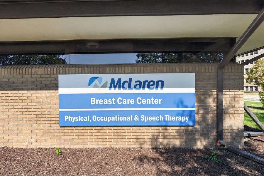 McLaren Breast Care Center sign on brick wall offering Physical, Occupational & Speech Therapy services.