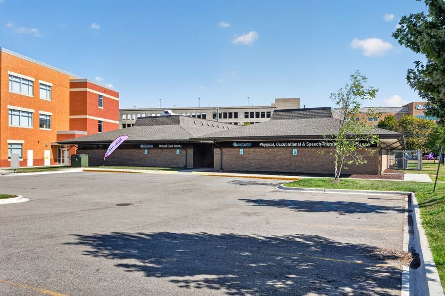 Brick school building with spacious parking lot under clear blue sky on a sunny day.