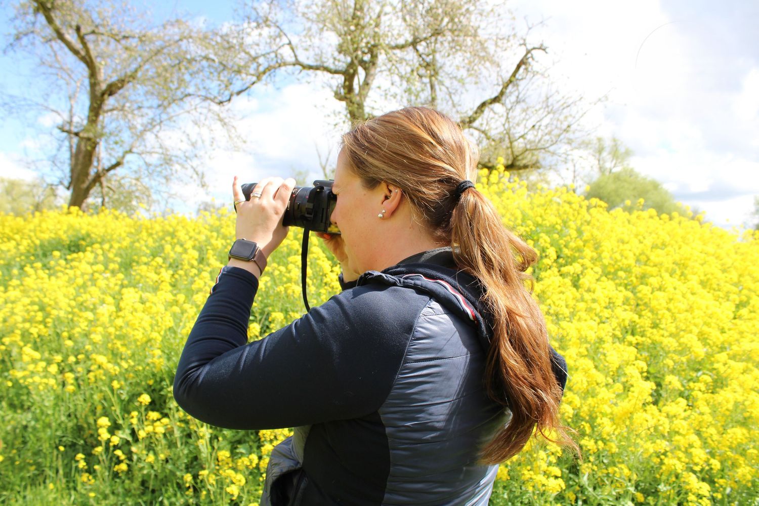 Meisje maakt foto tussen de gele bloemen.