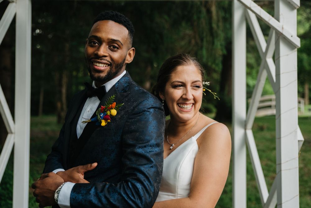 Newlyweds pose together outdoors against white architectural details.