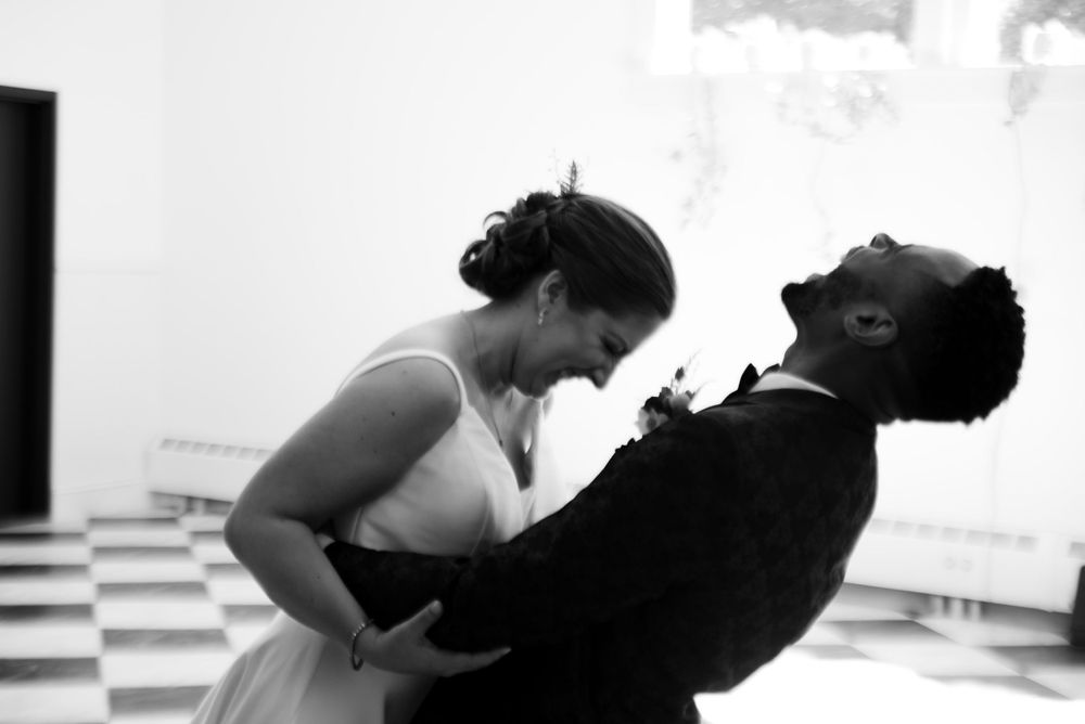 Black and white photo capturing playful moment between couple during wedding celebrations.