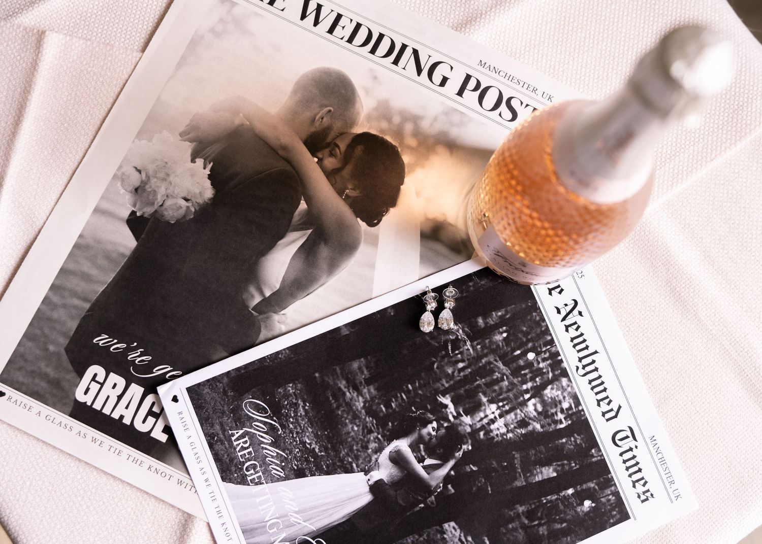 Wedding newspaper programs with a couple kissing photo, beside a rose wine bottle, elegant reception stationery.