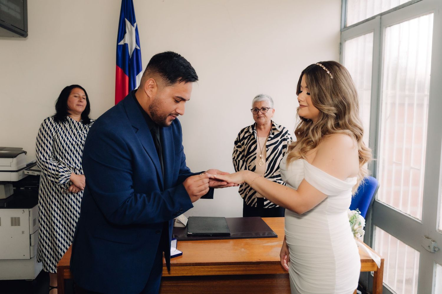 Groom placing wedding ring on brides finger during civil ring exchange ceremony.