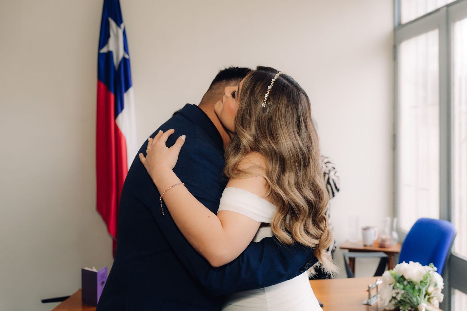 Bride and groom share a first kiss at a civil wedding ceremony with Chilean flag in background.