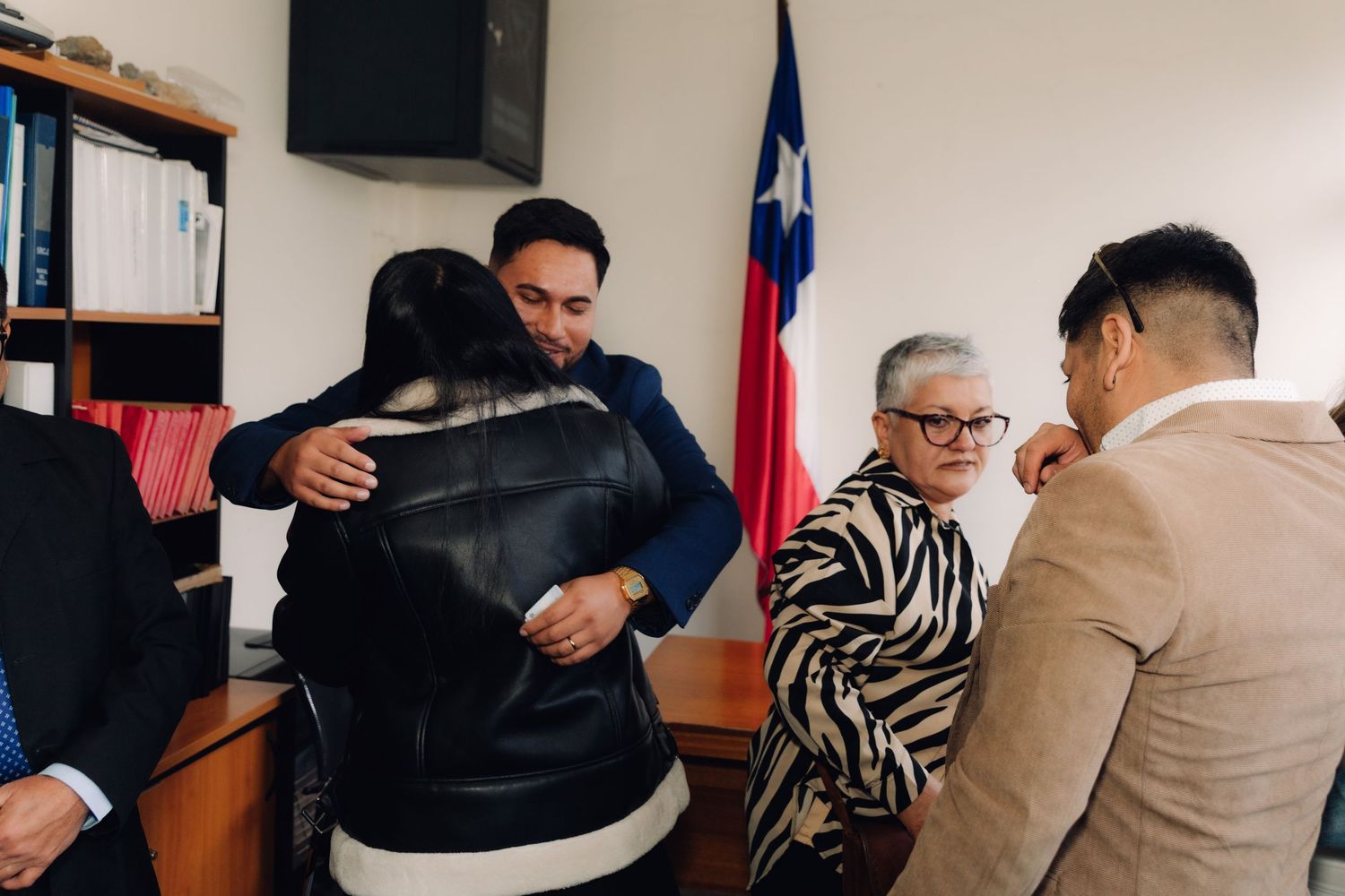 Groom hugs family member while others celebrate after civil wedding ceremony in Chile.
