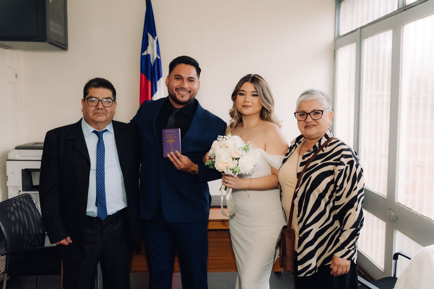 Newlyweds pose with family holding marriage certificate after civil wedding ceremony in Chile.