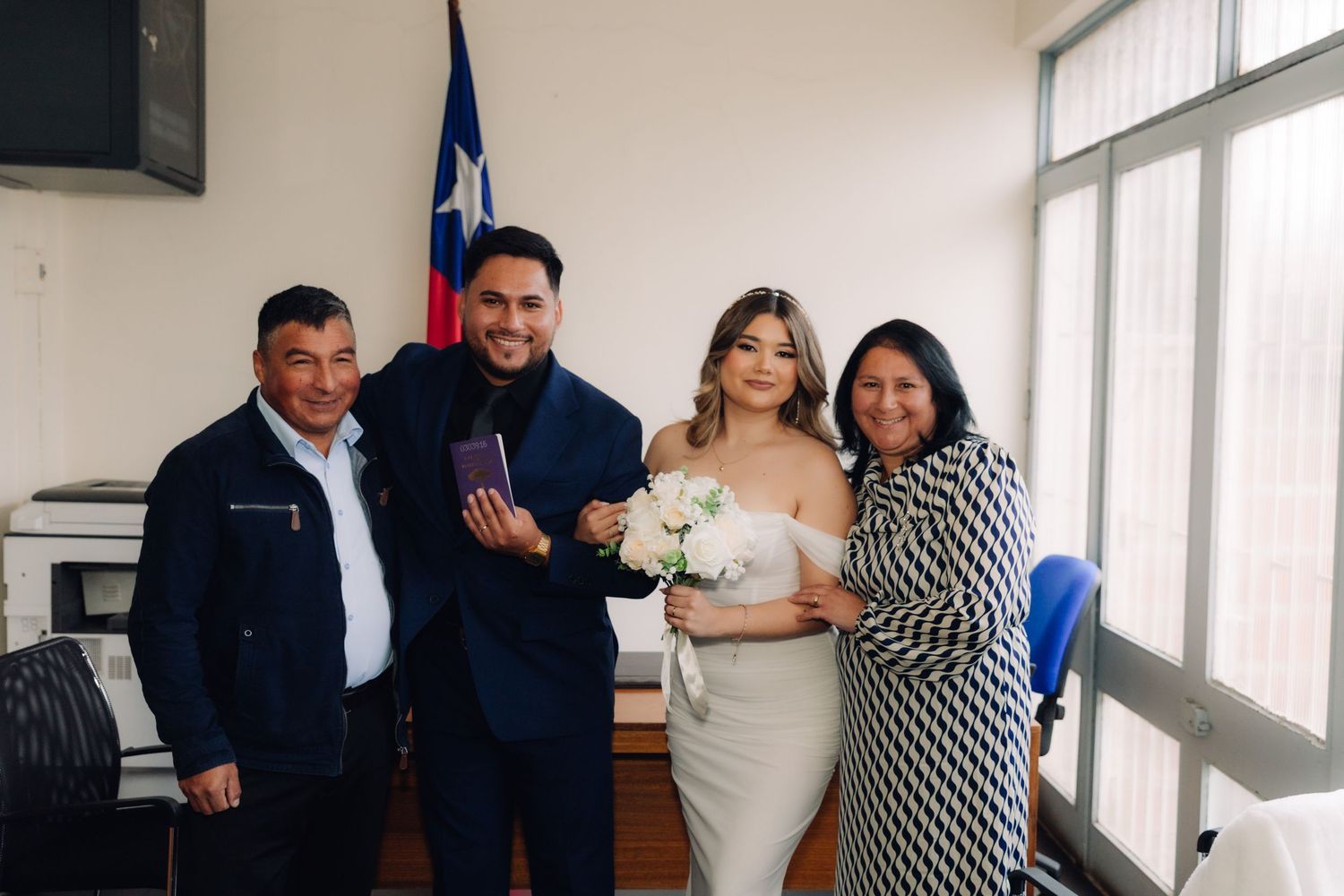Happy newlyweds and family pose together with marriage certificate after Chilean civil wedding.
