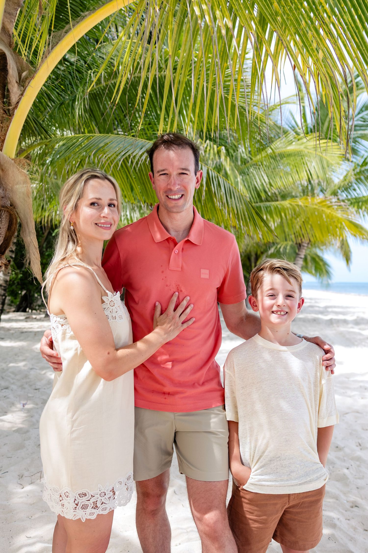 Happy family photoshoot posing on a tropical white sand beach under palm trees on a sunny day in Paradise beach cozumel