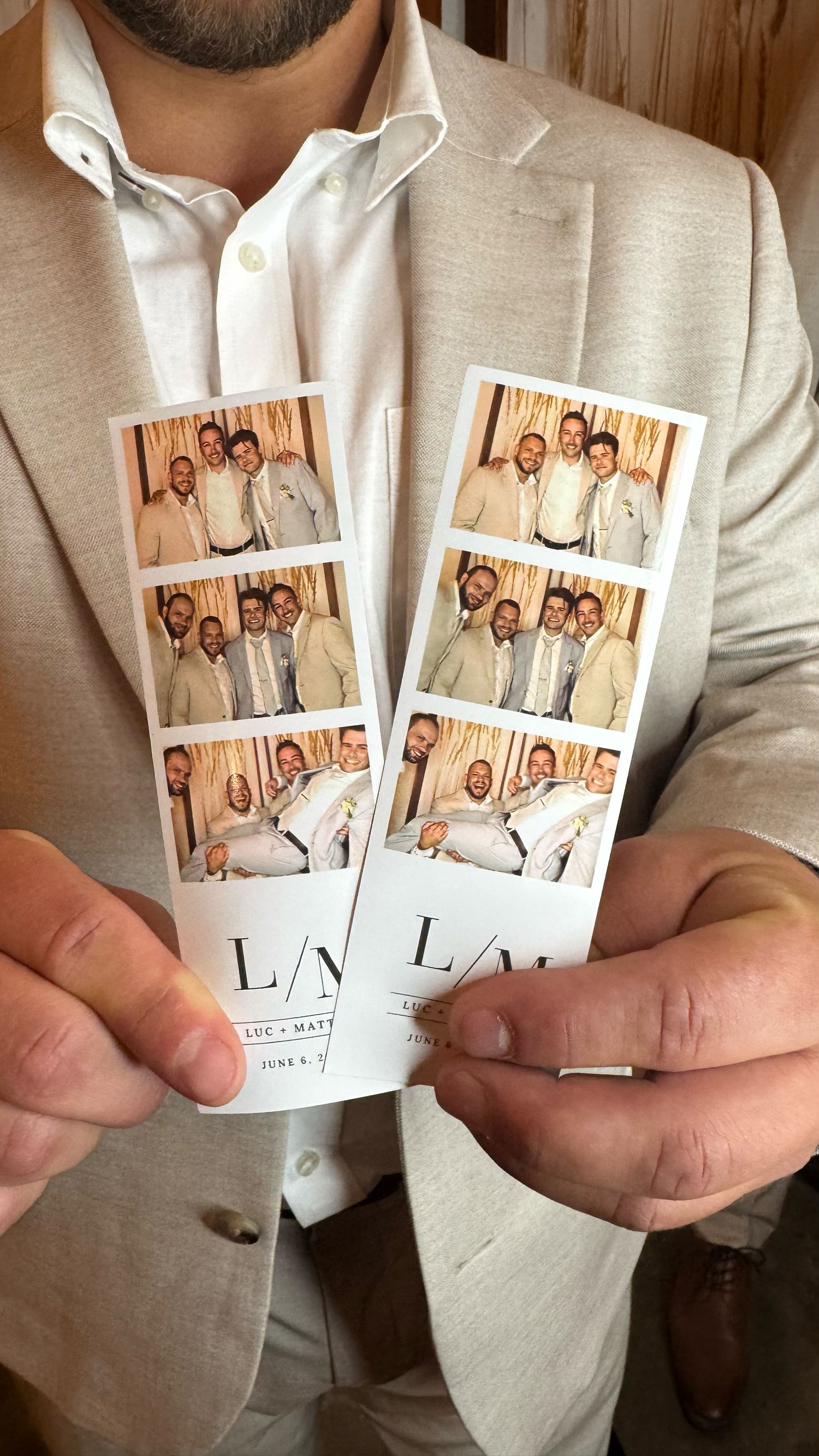 Man in beige suit holding two photo booth strips from a wedding with initials L/M, featuring group photos of men in suits.