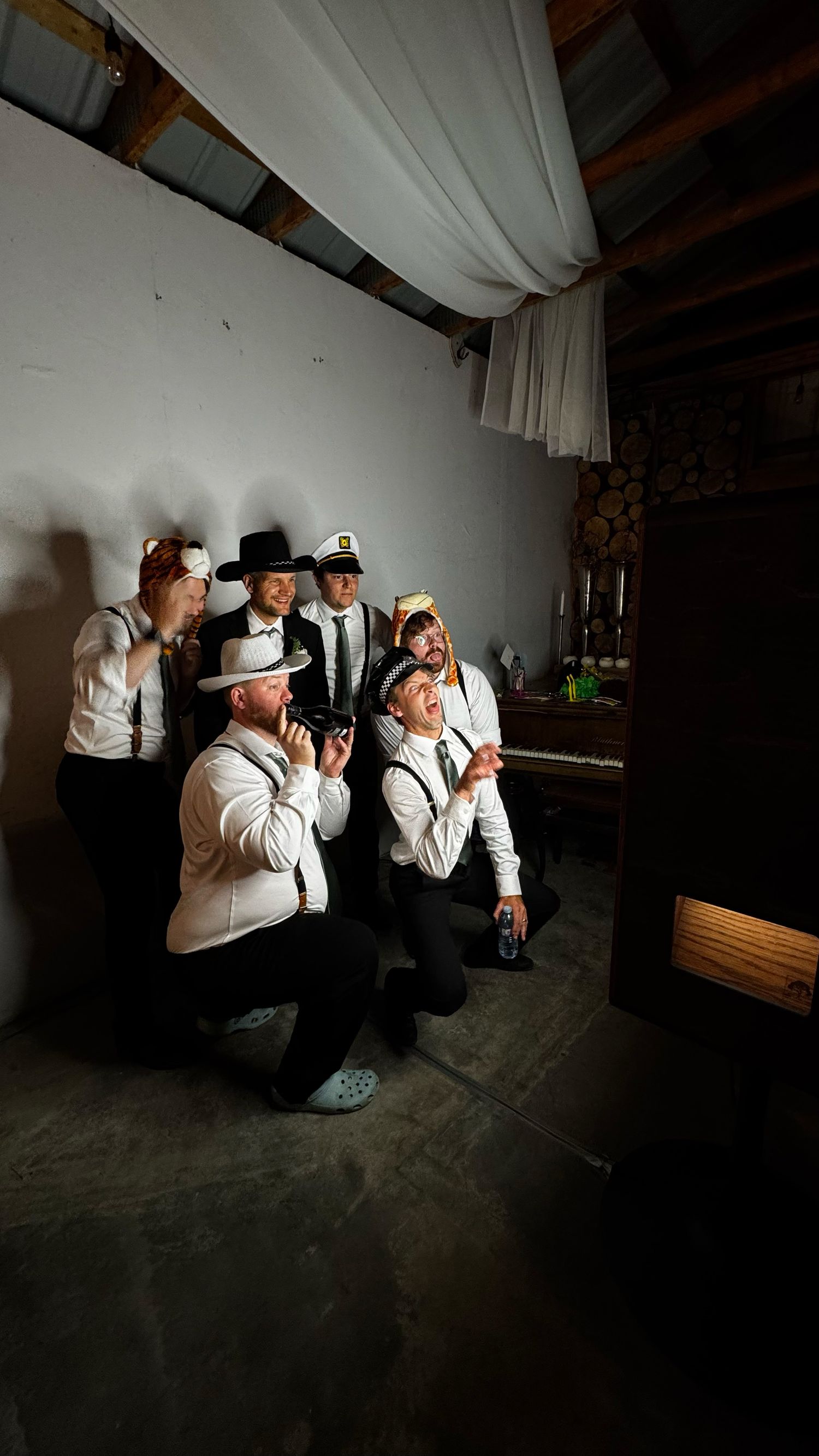 Group of people in white shirts and hats posing dramatically in a barn venue.