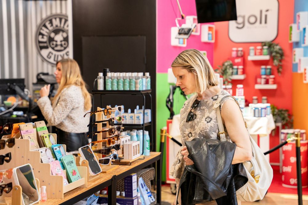 Two women shopping at a colorful retail store with Goli products and supplements displayed on shelves.
