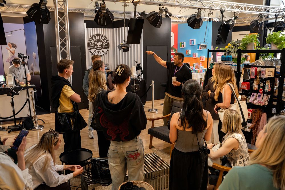 Group of people attending a photography studio demonstration with professional lighting equipment and camera setup.