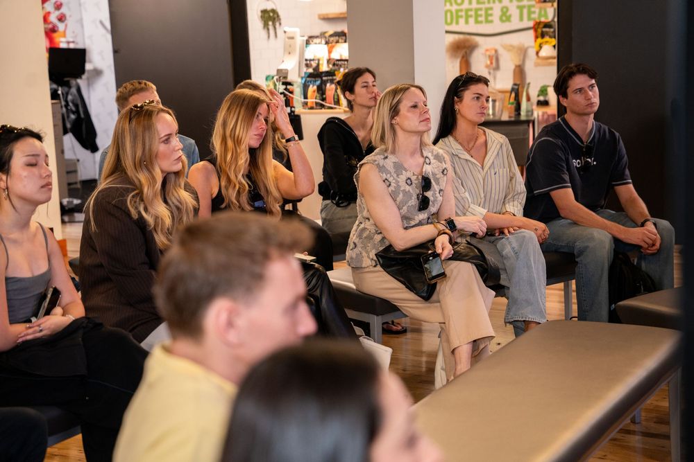 Group of people sitting and attentively watching a presentation in a modern coffee and tea shop.