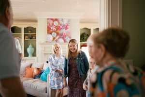 Two women smiling warmly in an elegant living room during a casual family gathering.