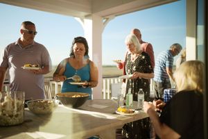 Adults enjoying a sunny outdoor patio party with food and drinks on a bright summer day.