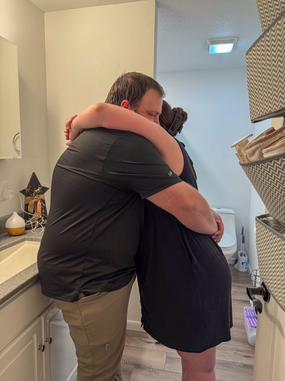 A couple shares a warm embrace in a modern bathroom during a meaningful moment.
