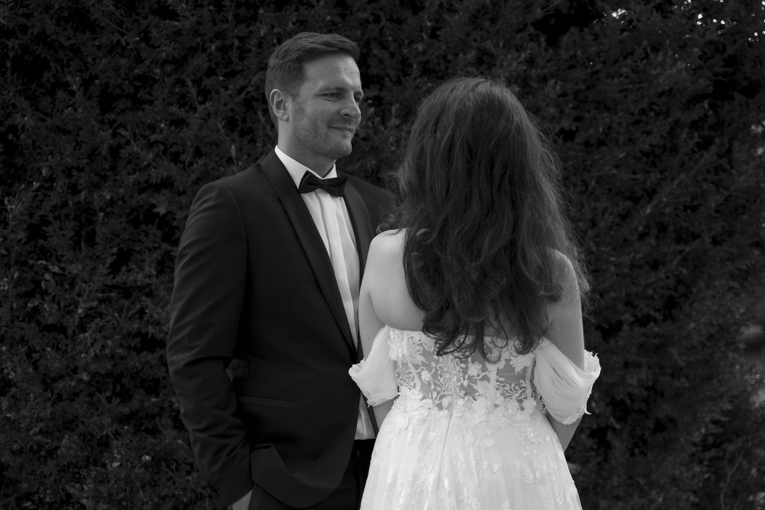 Black and white photo of bride and groom sharing romantic moment outdoors.