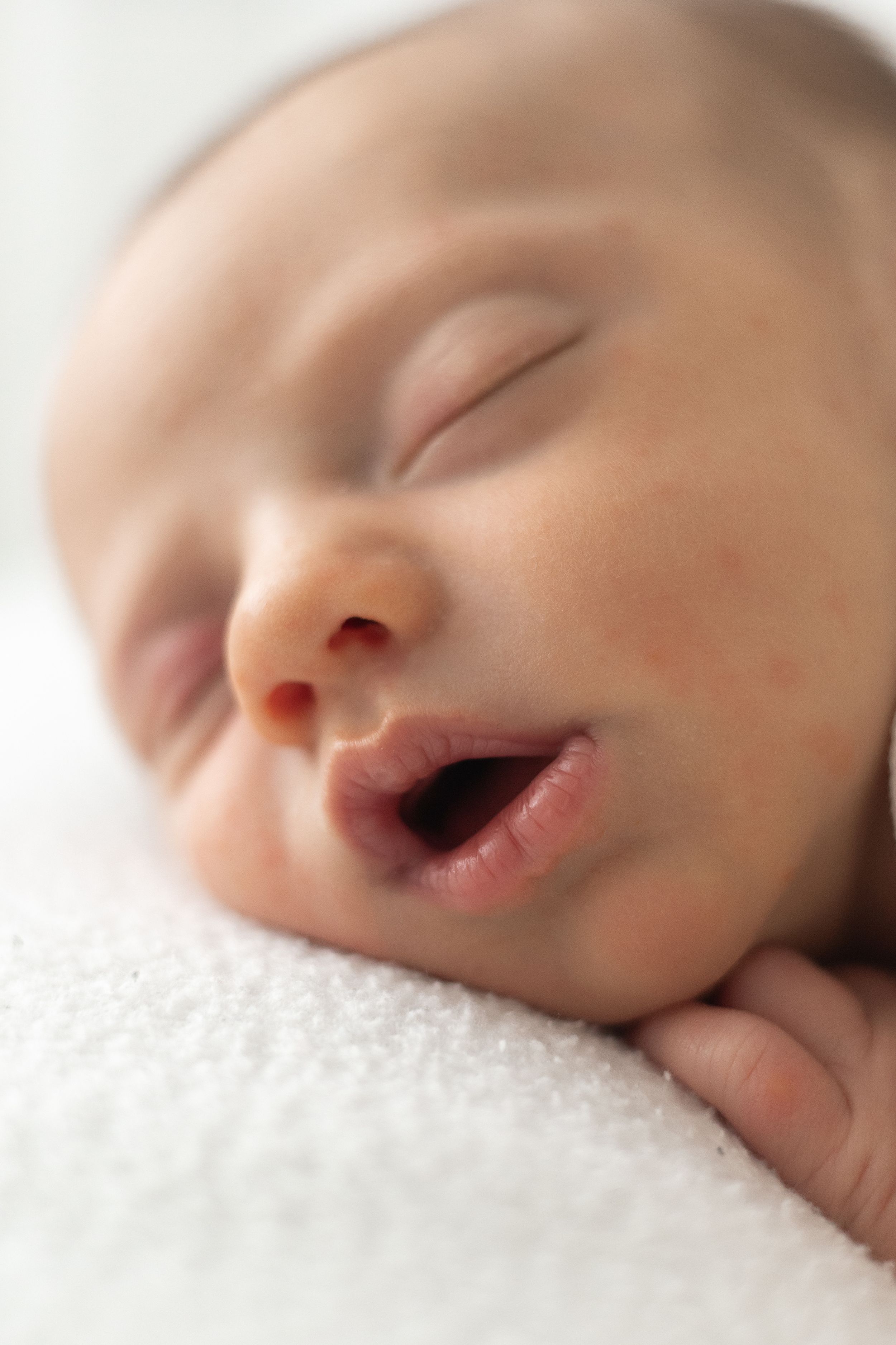 Close-up of a sleeping newborn baby, resting on a soft white blanket during newborn photographer Nottingham