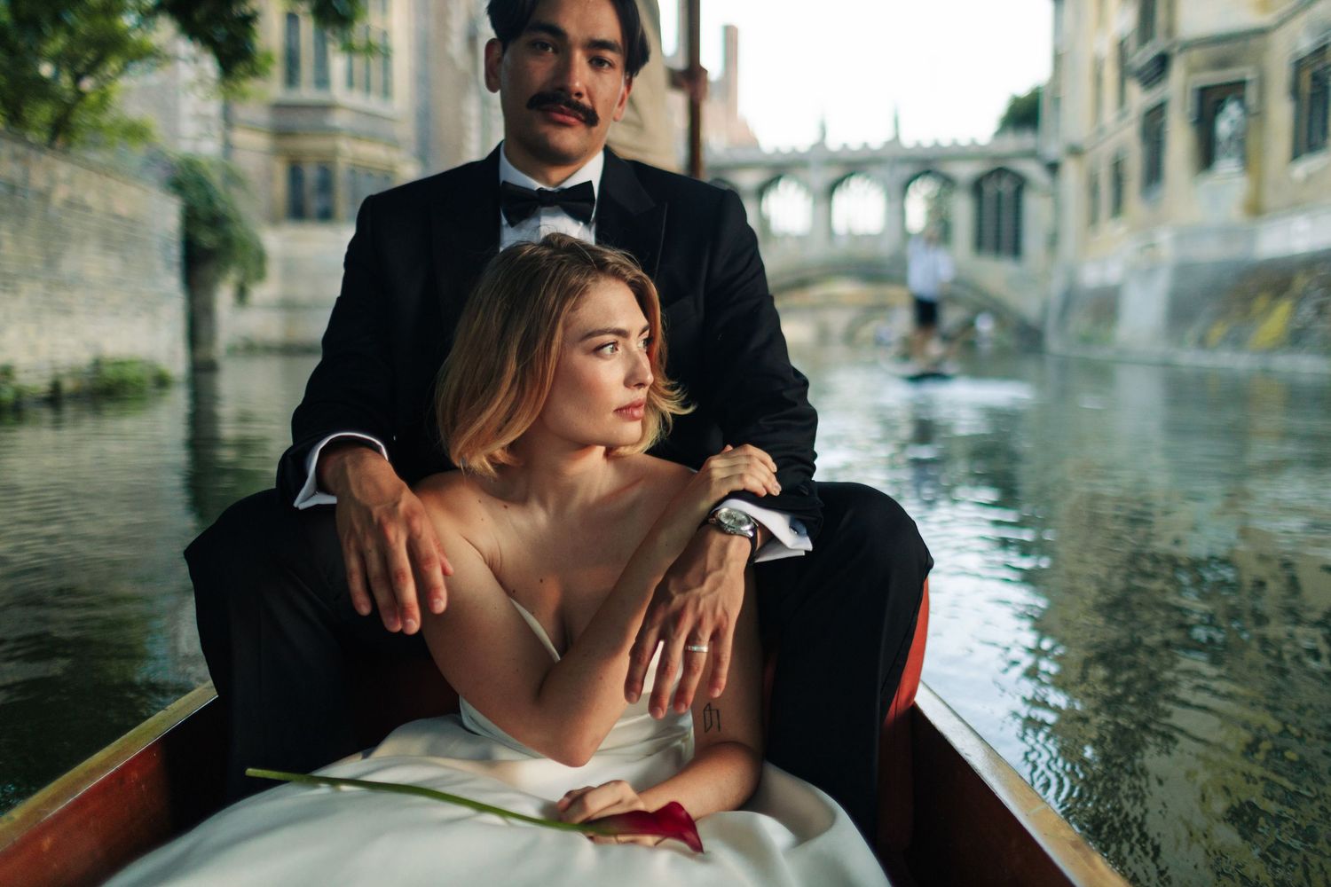 Bride and groom punting on River Cam with Bridge of Sighs in background, Cambridge, England.