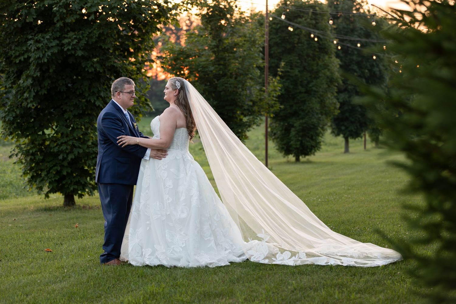 Bride and groom share a romantic sunset moment outdoors amid lush green trees at barn swallow fields in guelph, ontario.