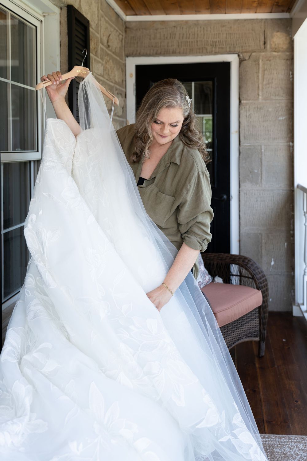 Bride admiring her lace wedding dress and veil, on the porch of an air bnb on the morning of her wedding in Guelph, Ontario.