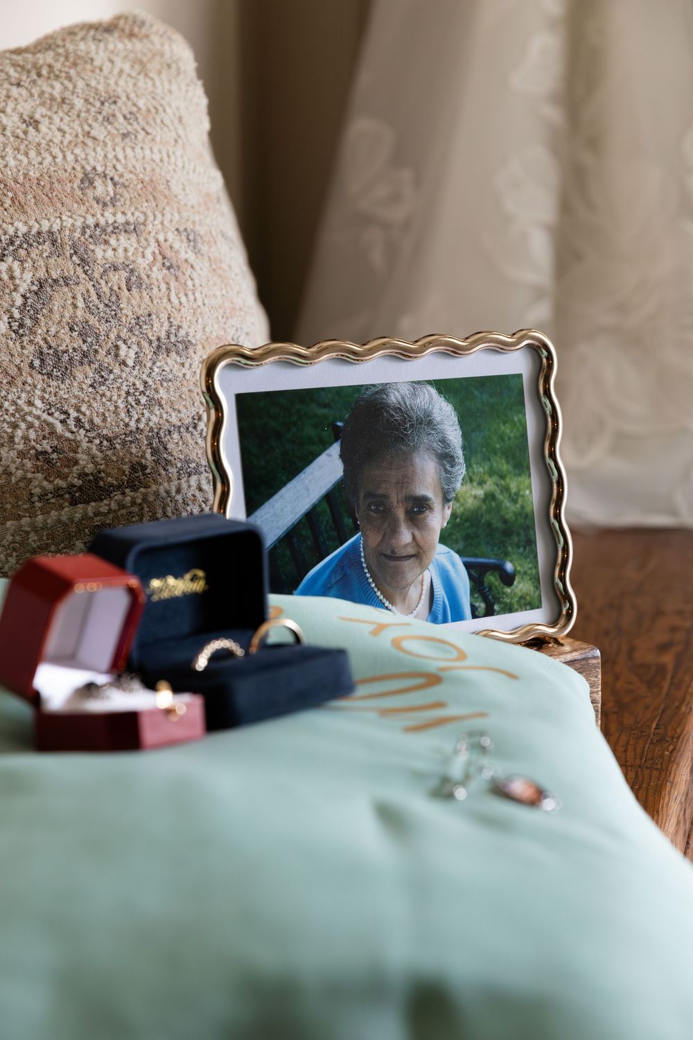 Framed photo of elderly woman on nightstand with jewelry boxes, rings, and necklace on green cloth pillow in Guelph, Ontario.