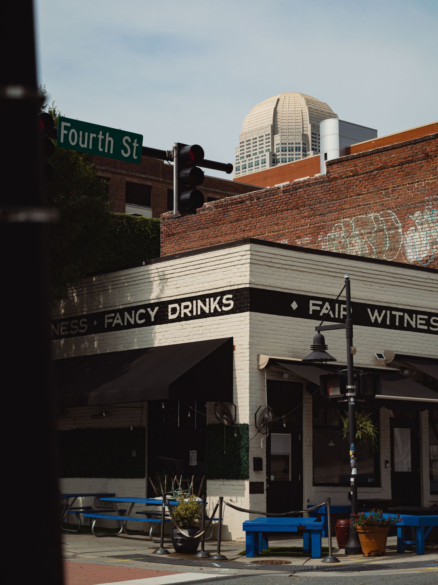 Corner bar with Fancy Drinks sign on Fourth St, brick building with city skyline dome visible behind it.