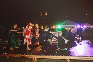 Guests dancing outdoors at a festive night event with colorful lights and a decorated venue in the background.