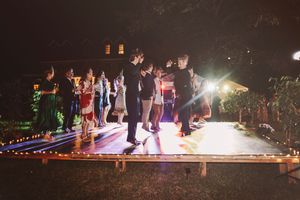 Guests dancing outdoors on illuminated dance floor at nighttime wedding reception party.