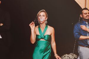 Woman in green halter dress blowing a bubble at a formal evening wedding reception event.