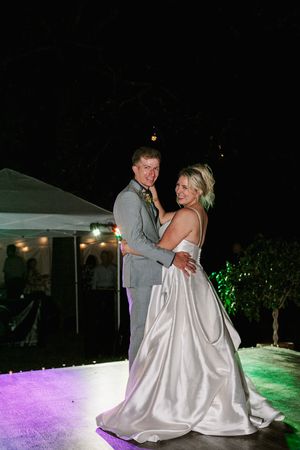 Bride and groom share their first dance on an outdoor illuminated dance floor at their evening wedding reception.