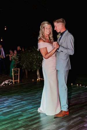 Mother and son share a special dance on a colorfully lit outdoor dance floor at a wedding reception.