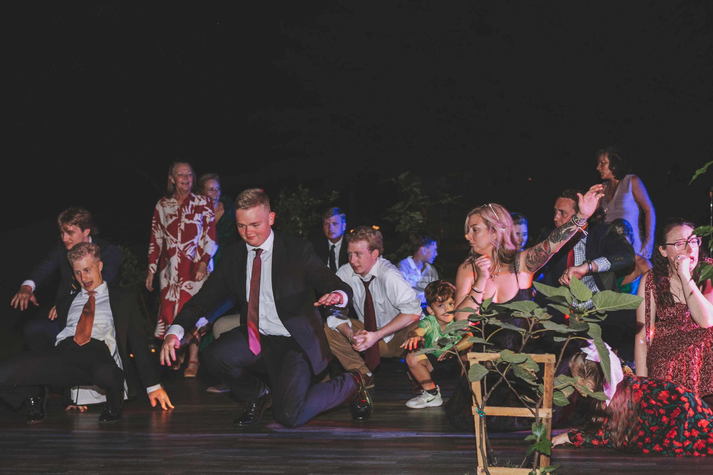 Guests in formal attire dancing and celebrating at an outdoor evening event or wedding reception.