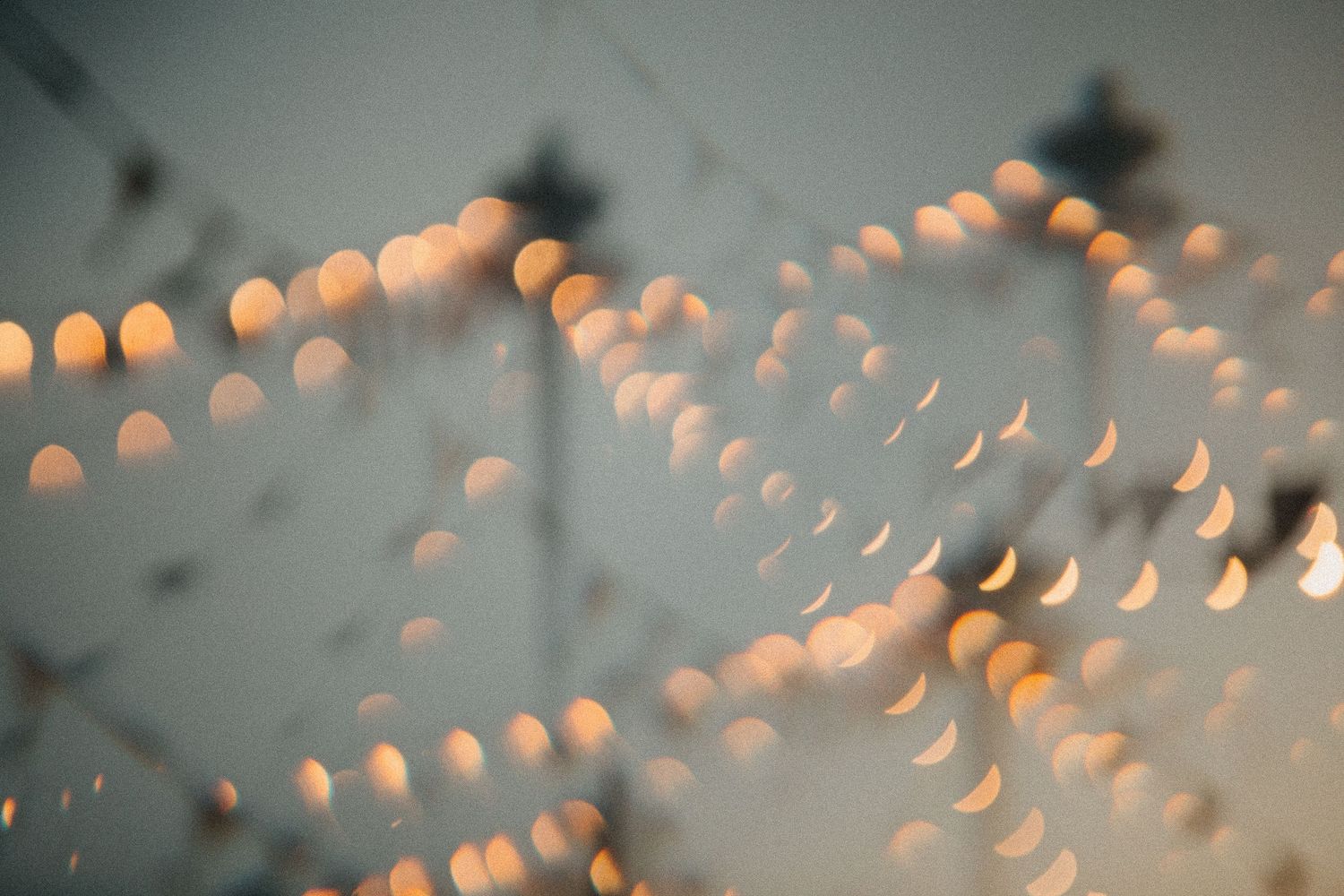 Blurred bokeh lights creating a dreamy, glowing pattern against a soft blue-gray background.