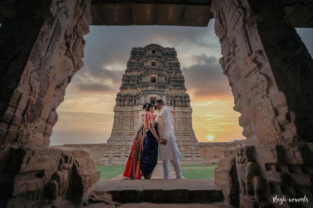 Couple posing at sunset before a stunning South Indian temple gopuram framed by ancient stone archway.