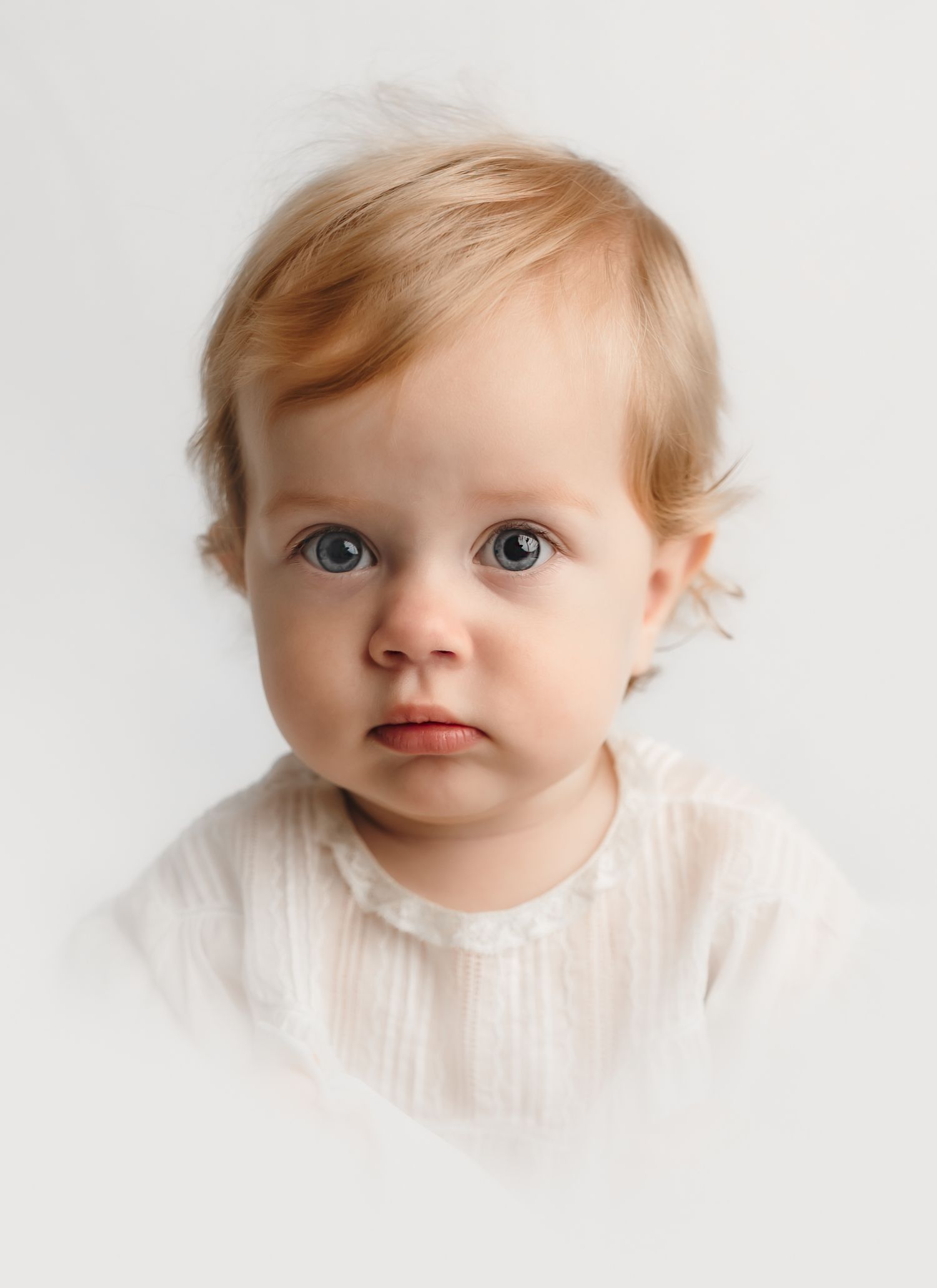 Baby girl with big blue eyes is captured as an heirloom vignette in an antique white dress by Charlottesville family photographer.
