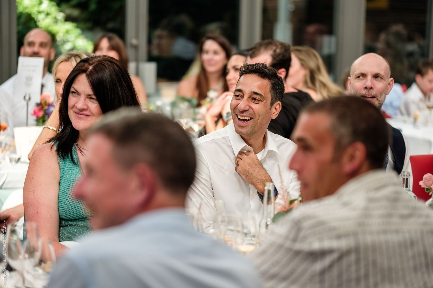 Guests laughing and enjoying conversation at an elegant wedding reception dinner table.