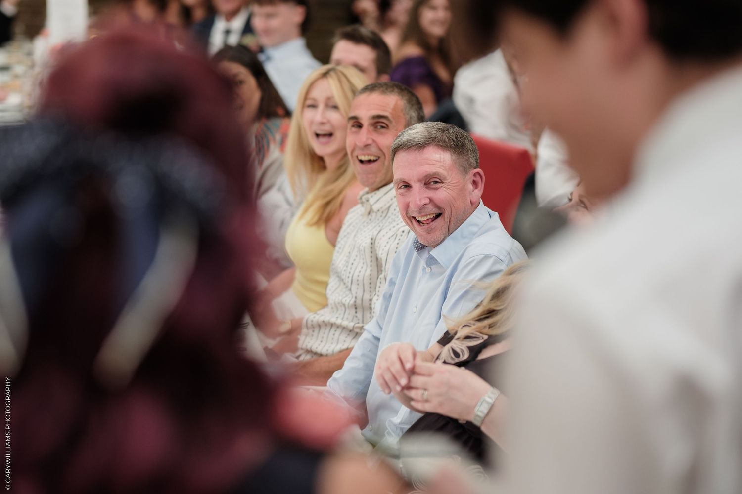 Audience members laughing and smiling at a live event, showing joy and engagement in a crowded venue.