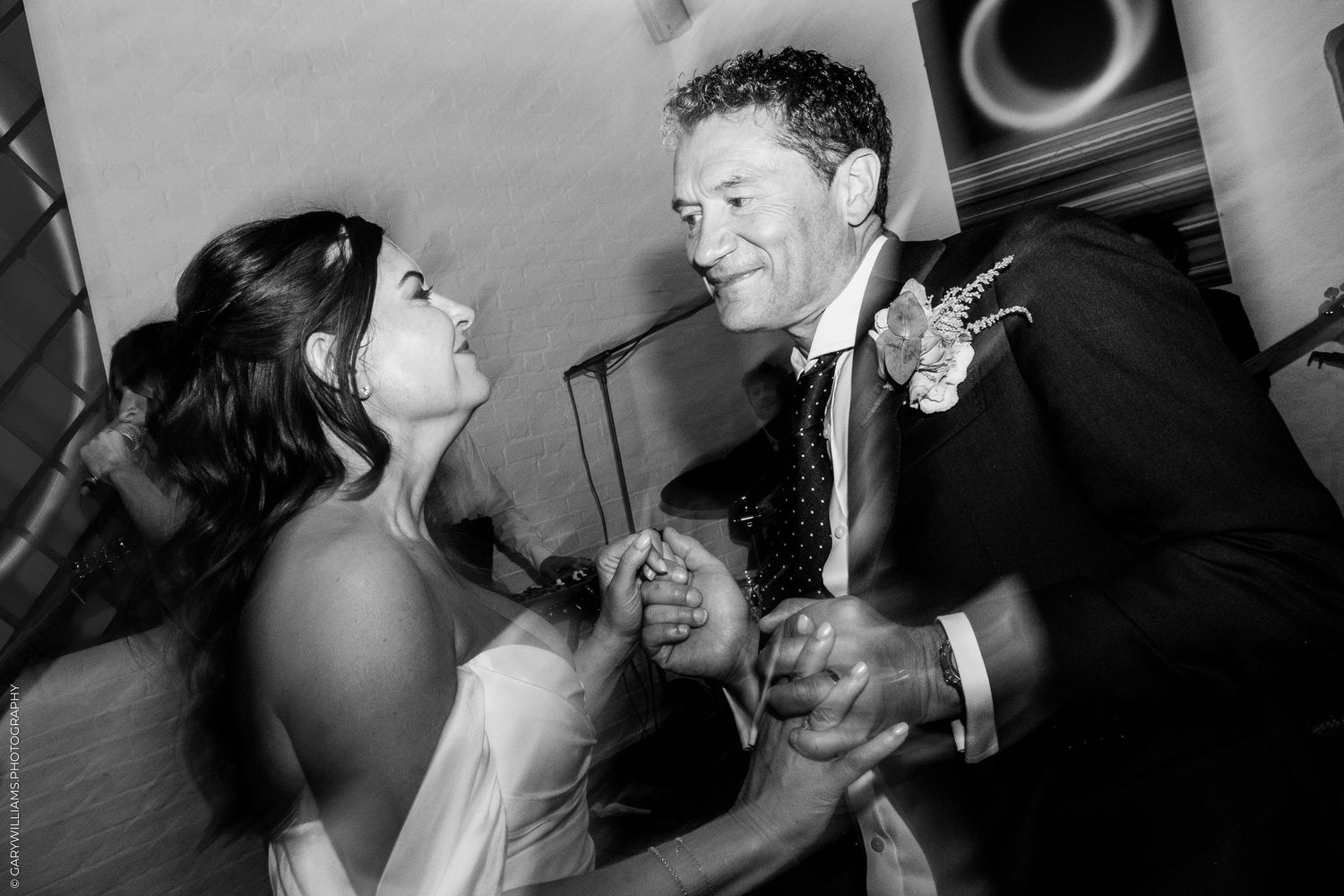 Black and white photo of a bride and groom sharing a joyful dance at their wedding reception.