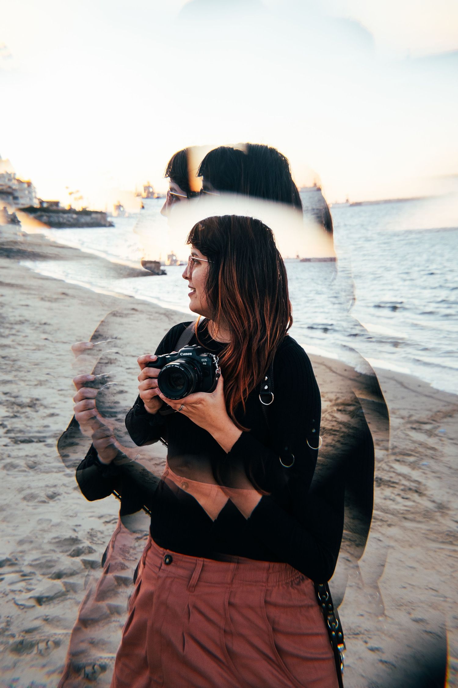 Photographer Kelsey Nevell holds camera while standing on a beach in San Diego.