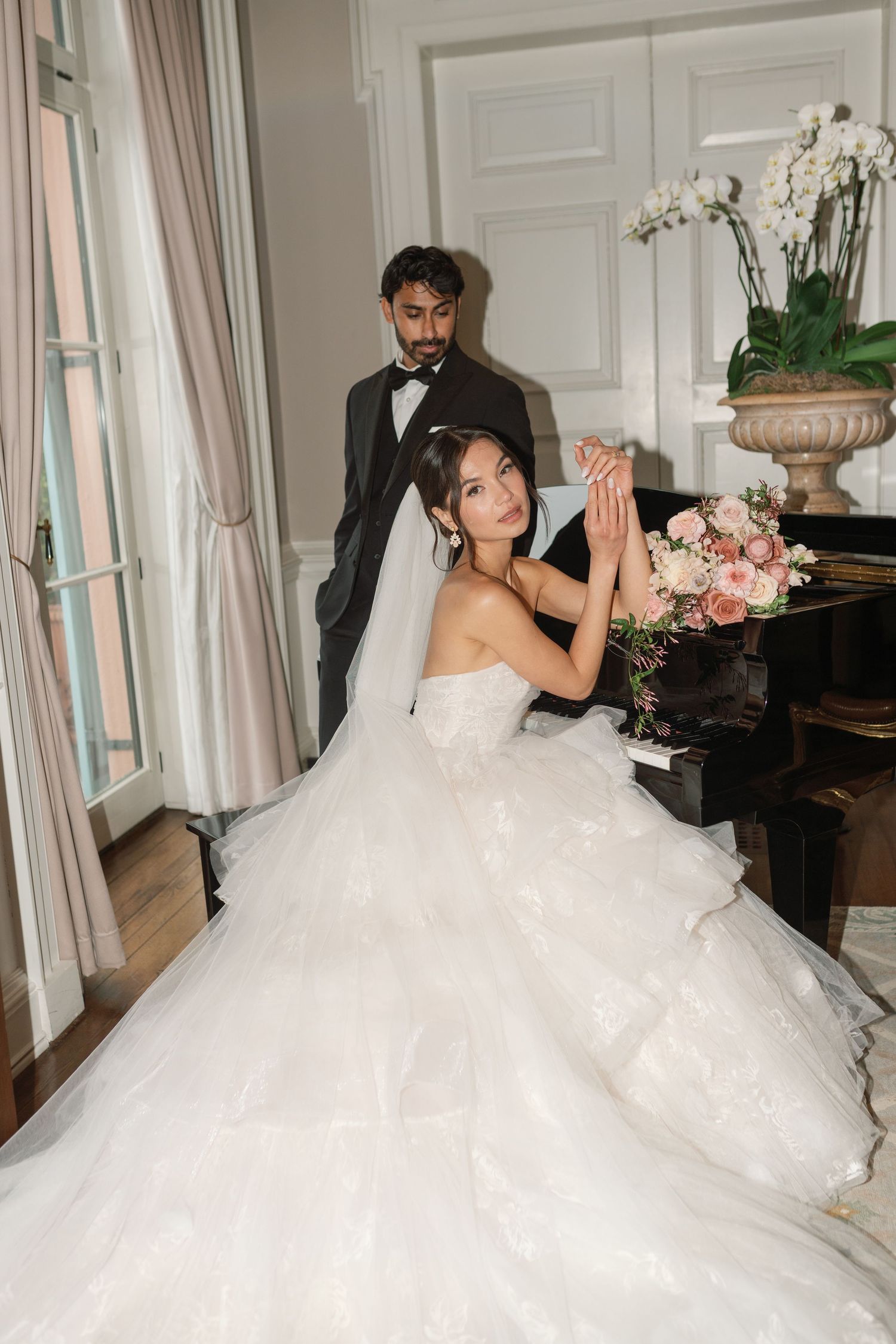 Wedding photographers capture bride in flowing dress through ornate doorway.