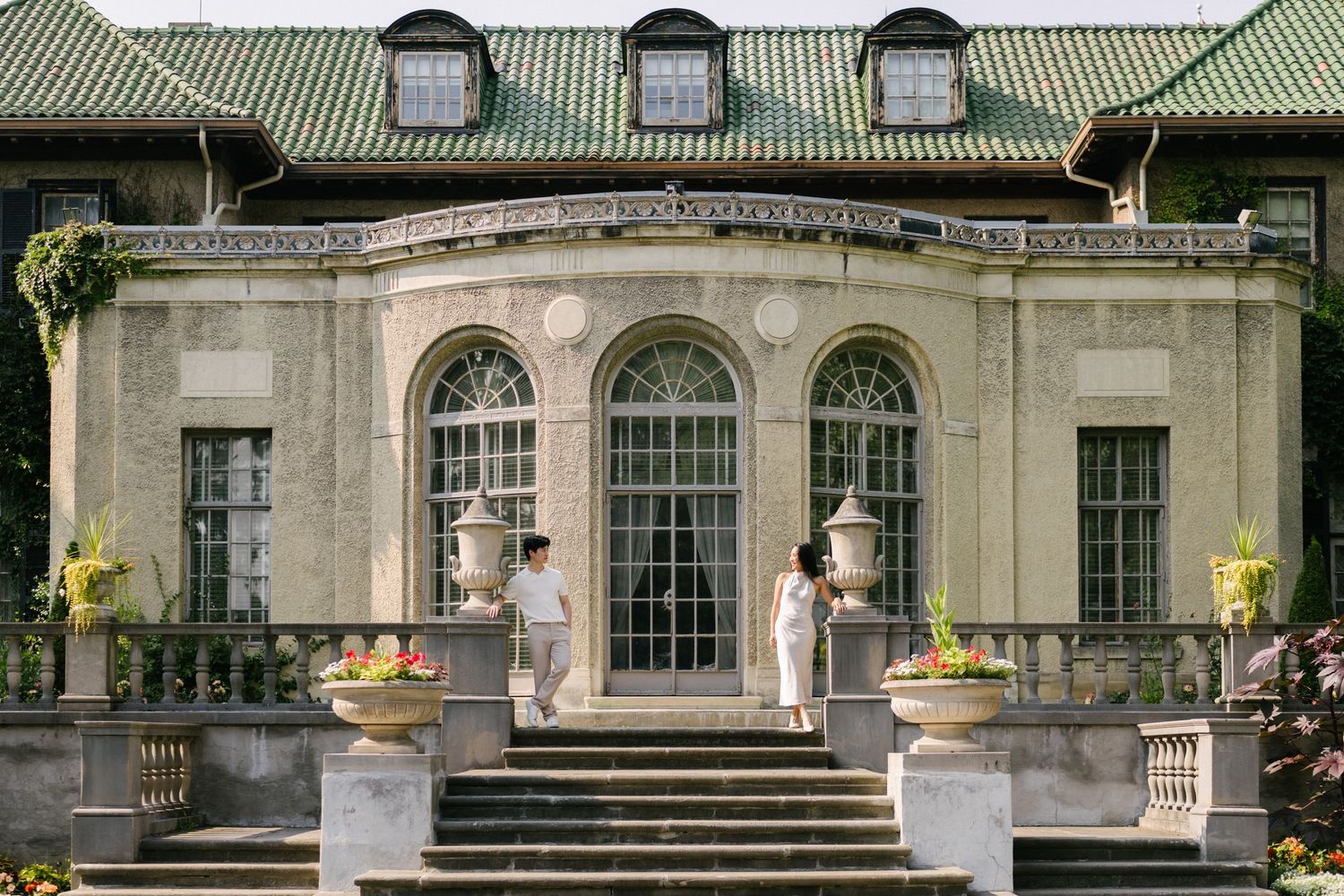 Bride and groom on the steps of a historic stone mansion.