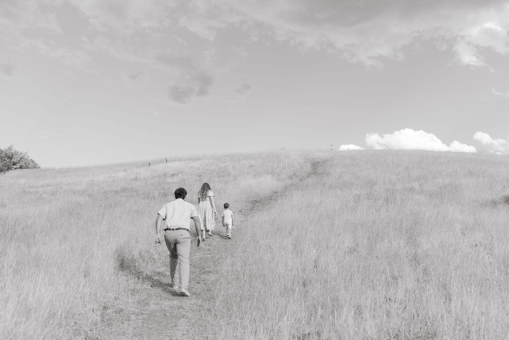 Black and white photo of a family walking along a path through a grassy hillside meadow.
