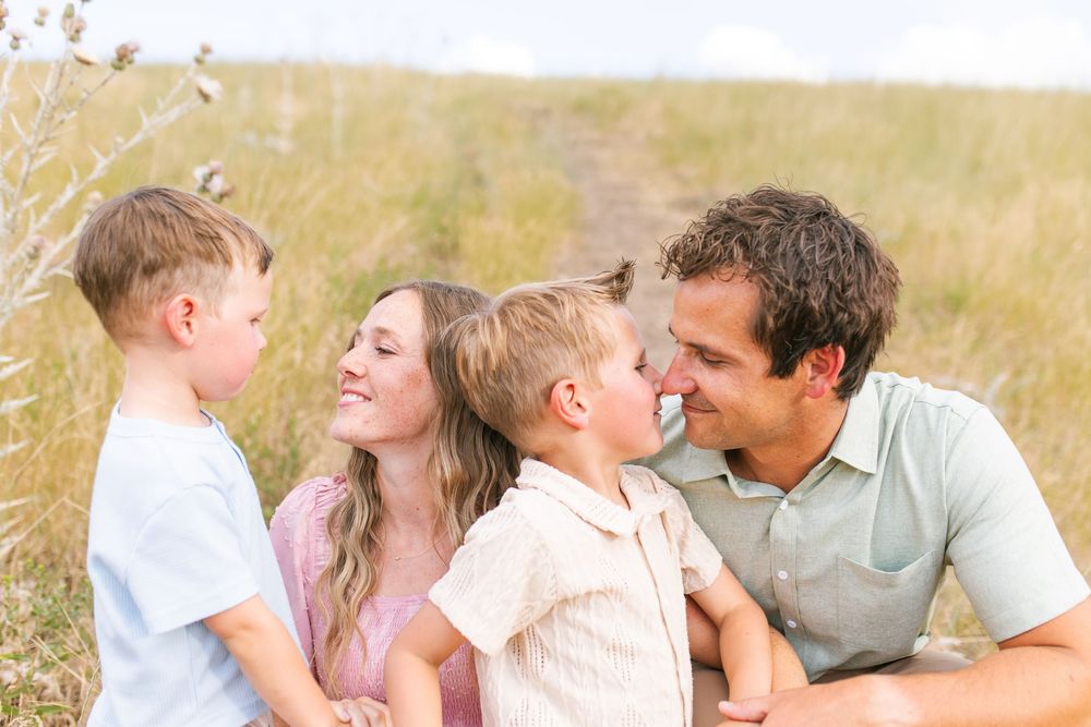 Happy family with two young boys sharing a joyful moment together in a golden field outdoors.