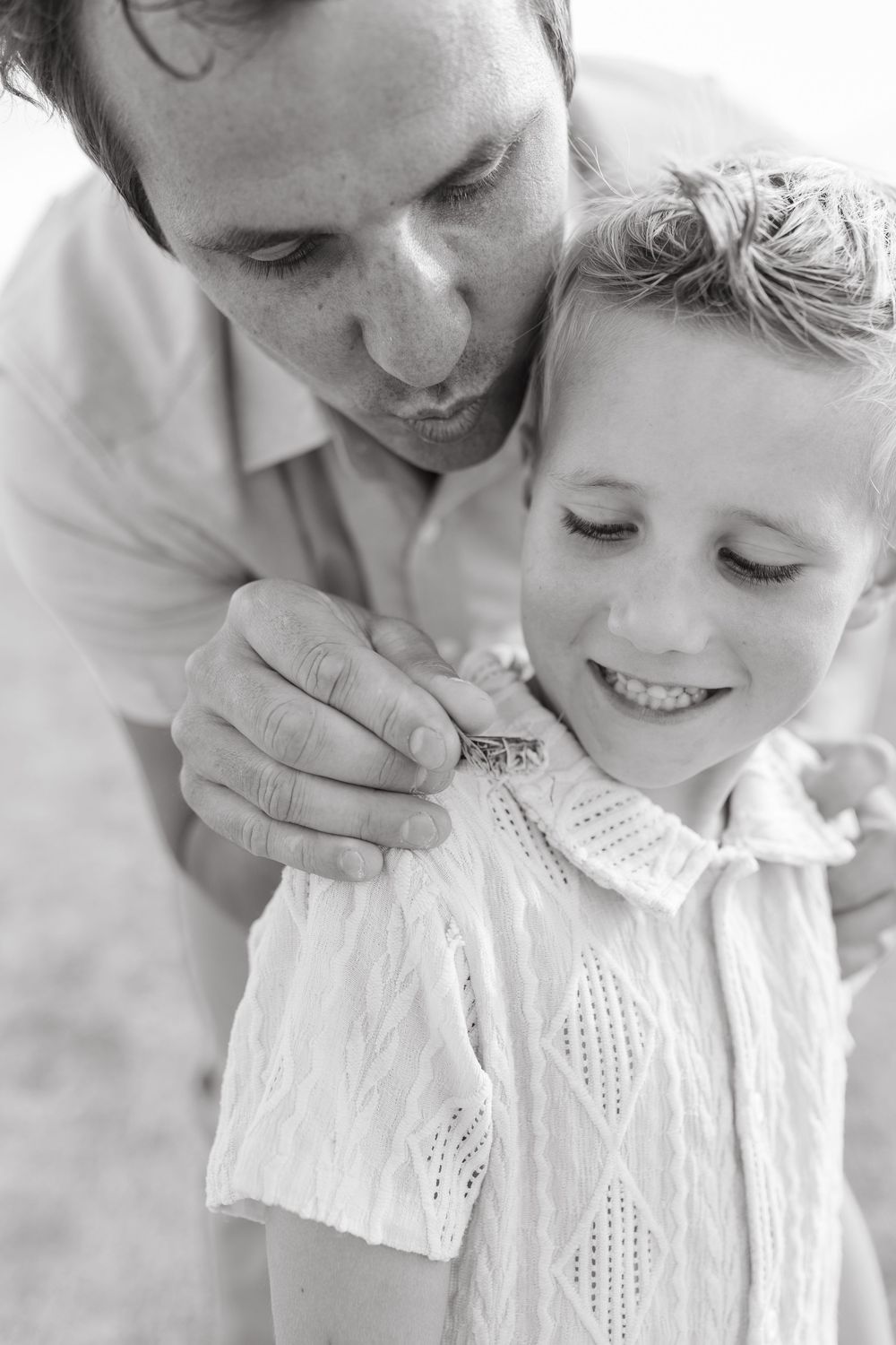 Black and white photo of father and young daughter sharing a tender moment examining a small object.