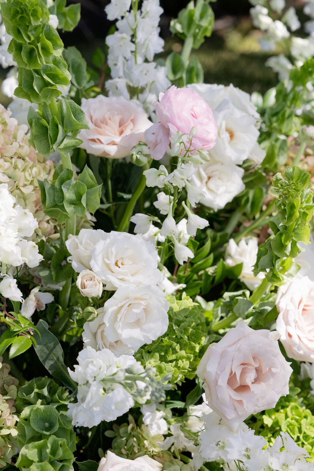 Lush wedding floral arrangement featuring white and blush pink roses with green foliage.