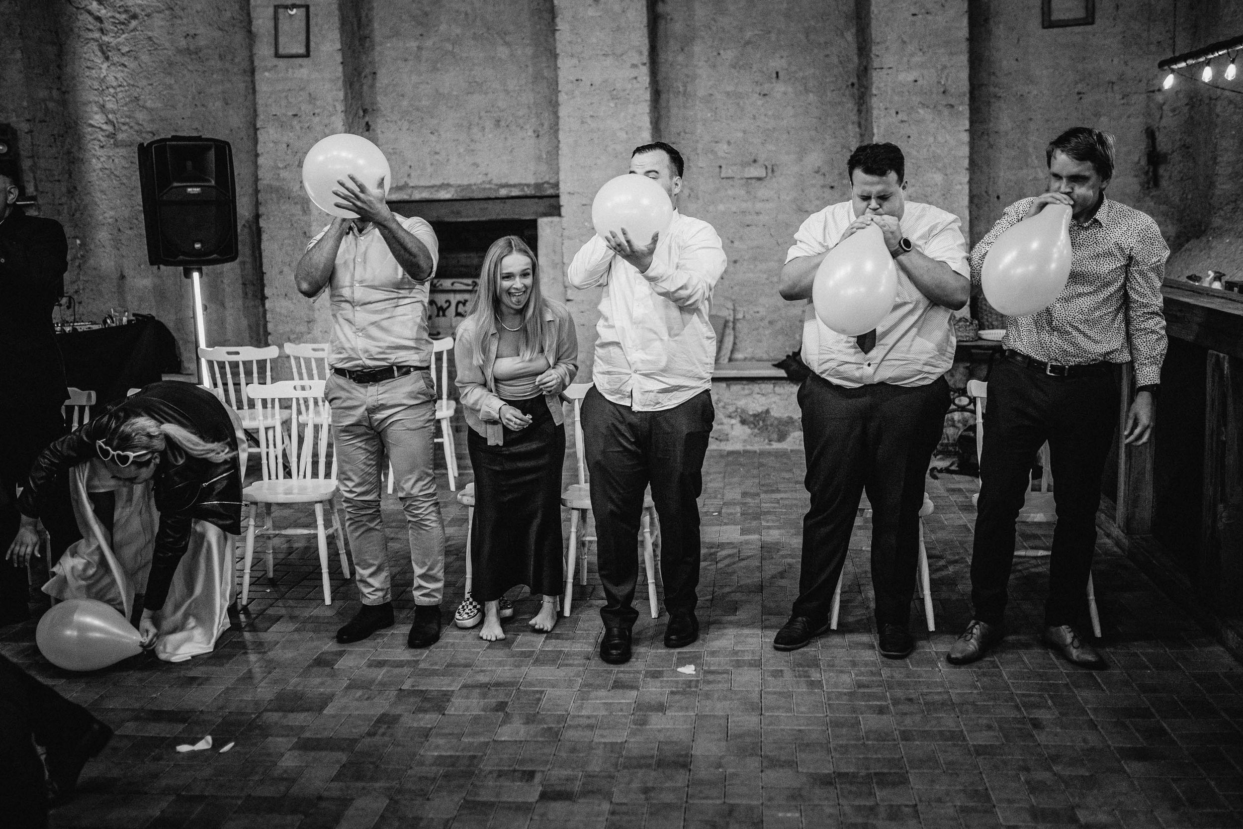 Skupina hostů při svatební zábavě ve stodole Statku Vitice – spontánní černobílá svatební fotografie.