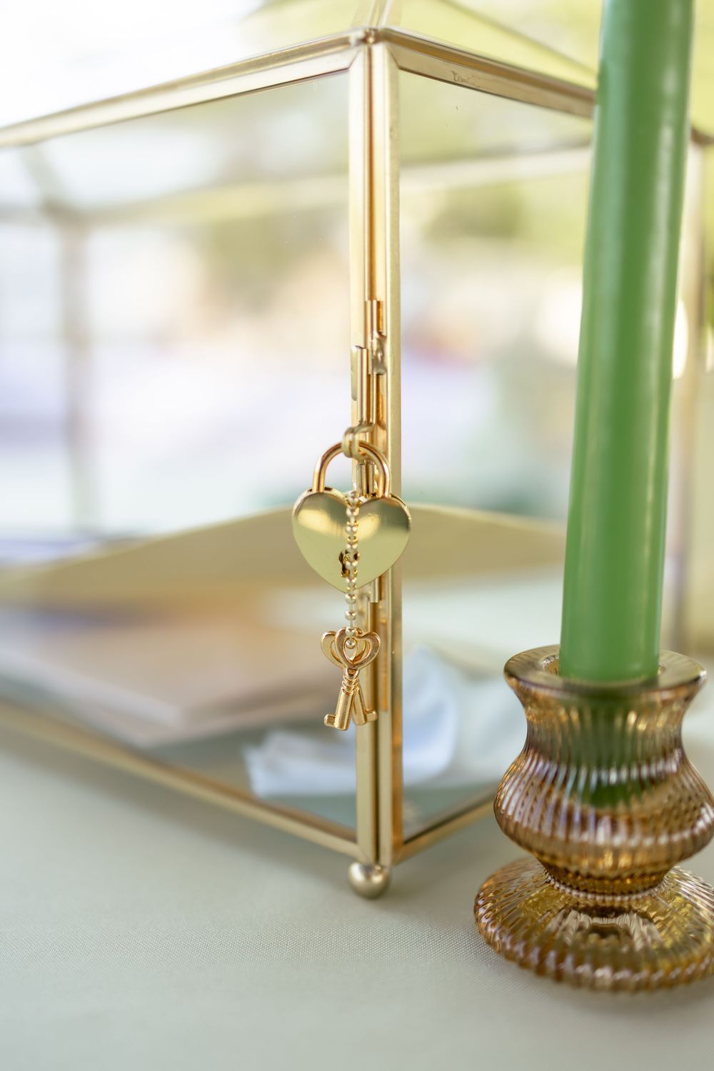 Wedding detail shot of a gold card box with a green tapered candle