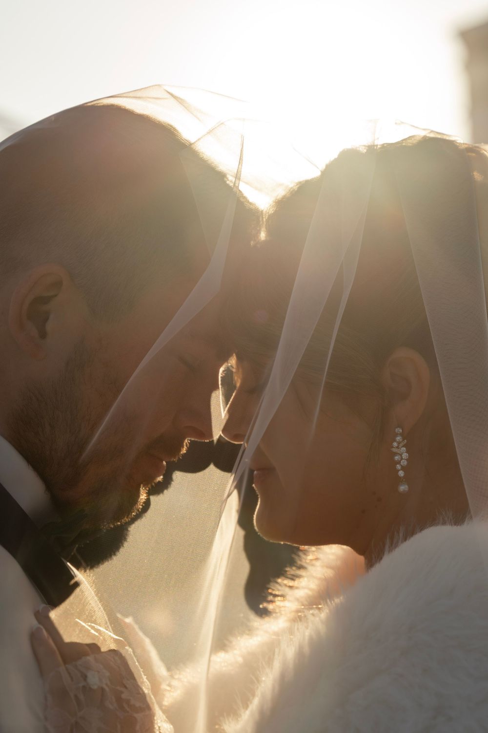 Bride and groom portrait at golden hour under bride's veil