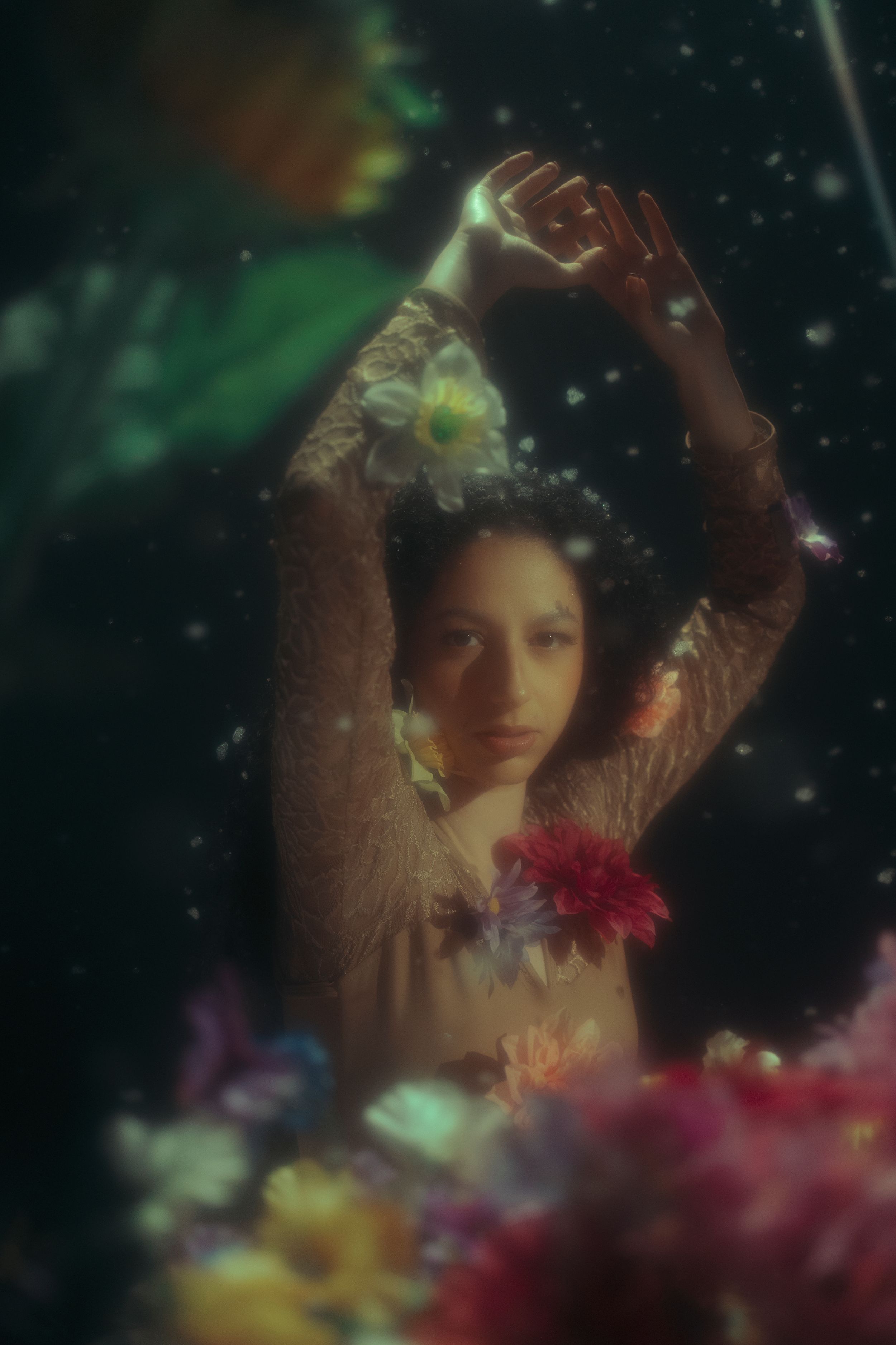 Cinematic floral portrait of a woman surrounded by colorful flowers with dramatic low-key lighting